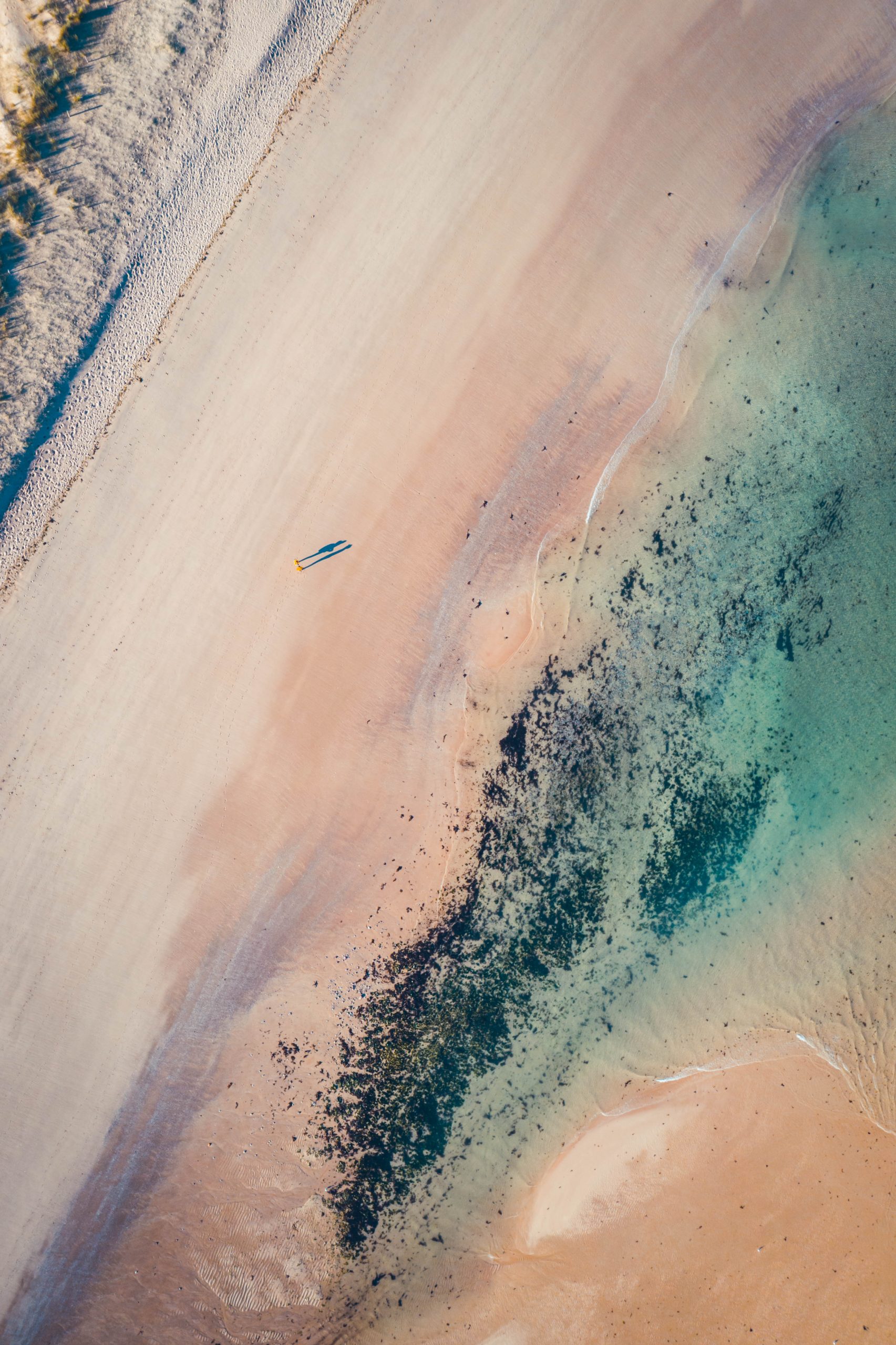 Une belle photographie de sable rosé mêlé aux eaux turquoise de la plage de Sables-d'Or-Les-Pins en Bretagne à l'ouest de la France. (La plage rosée de Sables-d'Or-Les-Pins en Bretagne)